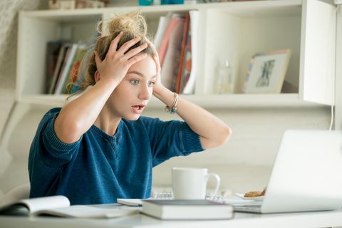 Frau sitzt vor Laptop und ist geschockt