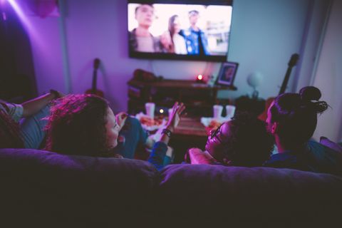 Drei Freunde sitzen vor einem Fernseher und unterhalten sich.