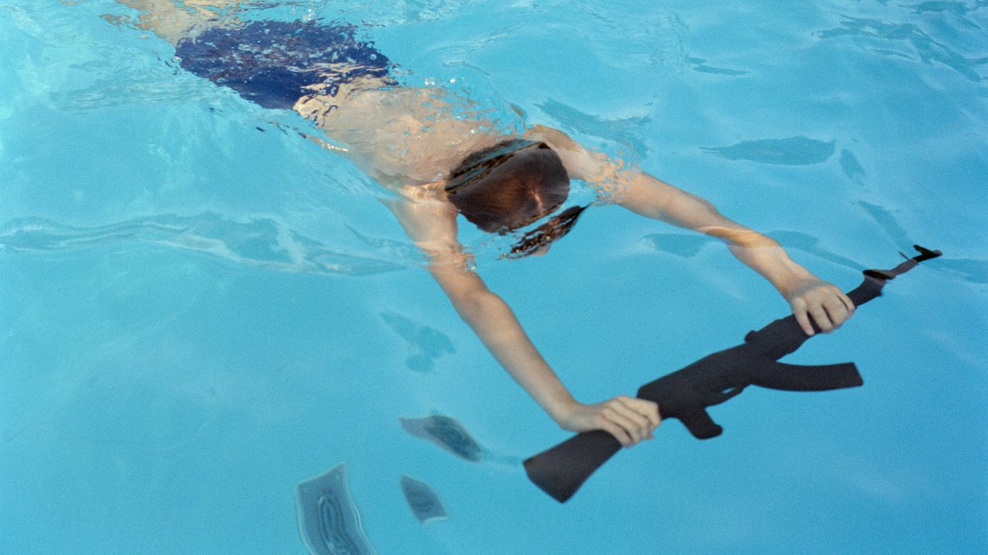 Mateusz übt das Schwimmen mit einer Waffe in einem Sommer-Militärlager im polnischen Mrzeżyno. Die Organisatoren behaupten, dass die Teilnahme mit Waffennachbildungen Kinder daran hindert, echte Waffen zu suchen.