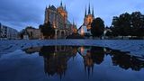 Erfurt, Deutschland. Mariendom und Severikirche spiegeln sich im Morgengrauen in einer Pfütze auf dem Domplatz