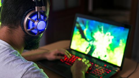 Ein Mann sitzt vor einem Laptop und spielt daran