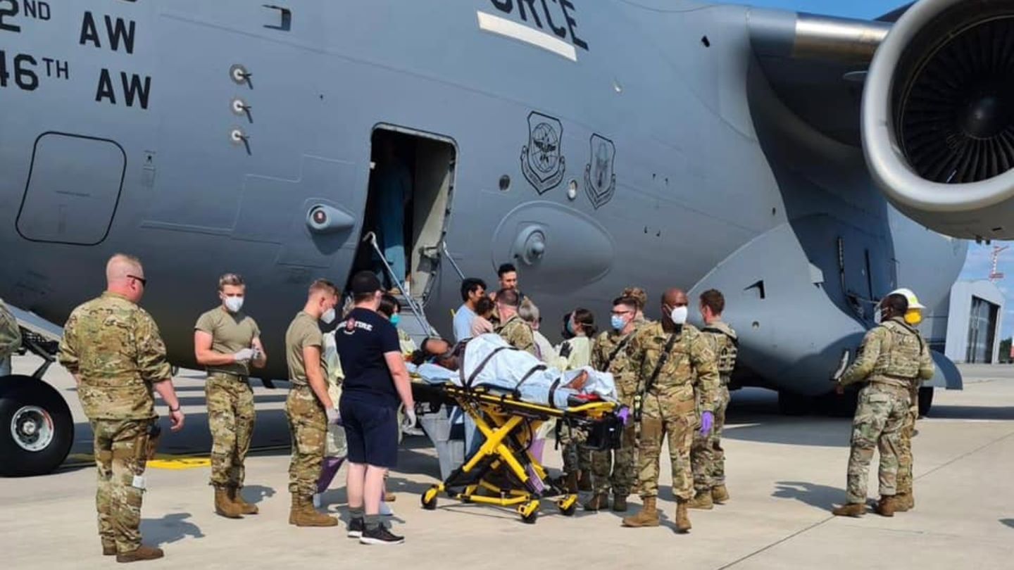 Flugzeug, Militär und die Mutter auf einer Trage auf dem Rollfeld