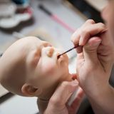 Eine neue Babypuppe ist in der Produktion. Um die Puppen wie echte Babys aussehen zu lassen, braucht es viel Geduld und Liebe zum Detail. Meist werden sie aus Vinyl oder aus Silicon gefertigt. Die Wimpern bestehen aus Echthaar. Am Ende werden die Puppen mit einem "Babyduft" einparfümiert.