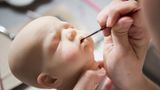 Eine neue Babypuppe ist in der Produktion. Um die Puppen wie echte Babys aussehen zu lassen, braucht es viel Geduld und Liebe zum Detail. Meist werden sie aus Vinyl oder aus Silicon gefertigt. Die Wimpern bestehen aus Echthaar. Am Ende werden die Puppen mit einem "Babyduft" einparfümiert.
