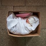 Fertig zur Adoption: Eine frisch gefertigte Babypuppe liegt bereit, um an ihre neuen "Eltern" geschickt zu werden. Das Paket beinhaltet eine Geburtsurkunde und ein Set Baby-Kleidung. Für die "Eltern" ist der Moment des Entpackens etwas ganz Besonderes. Viele filmen das Ereignis, um es in den sozialen Medien zu teilen.