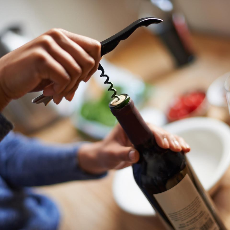 Weinöffner: Mann öffnet Weinflasche mit einem Kellnermesser