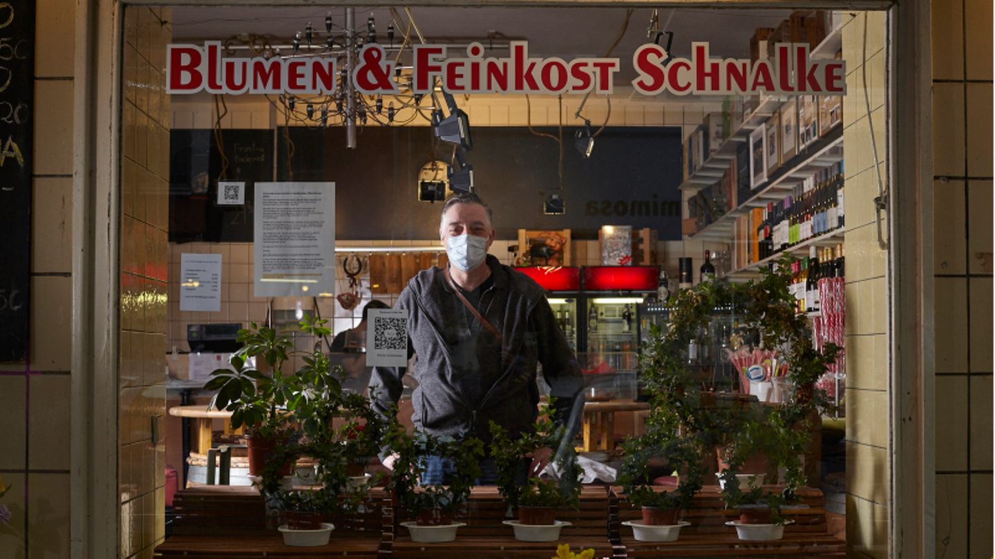 Uwe Schnalke trägt eine Mund-Nasen-Bedeckung und sieht durch das Schaufenster seines Ladens