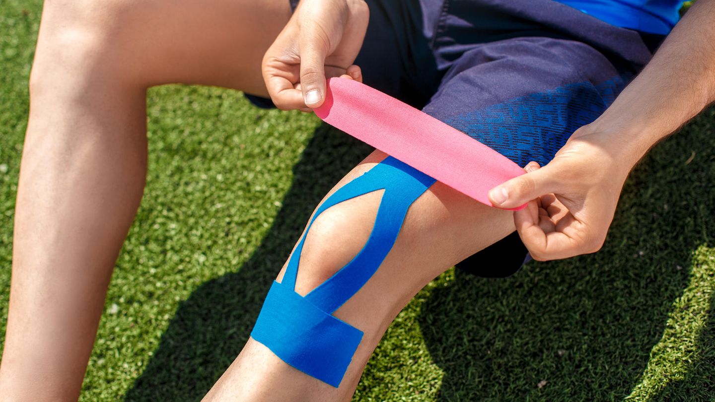 Kinesiotape: Mann behandelt sein Knie mit Kinesiotapes