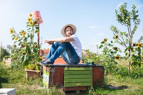Ein junger Mann sitzt im Garten, er sieht nachdenklich aus