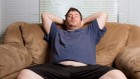 Ein Mann sitzt mit geschlossenen Augen auf dem Sofa
