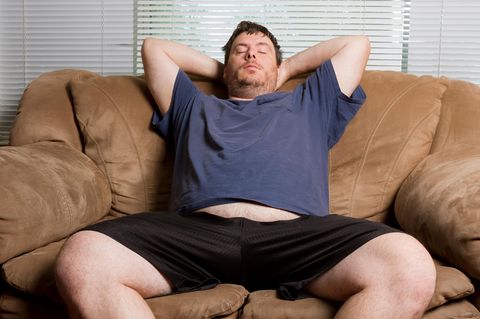 Ein Mann sitzt mit geschlossenen Augen auf dem Sofa