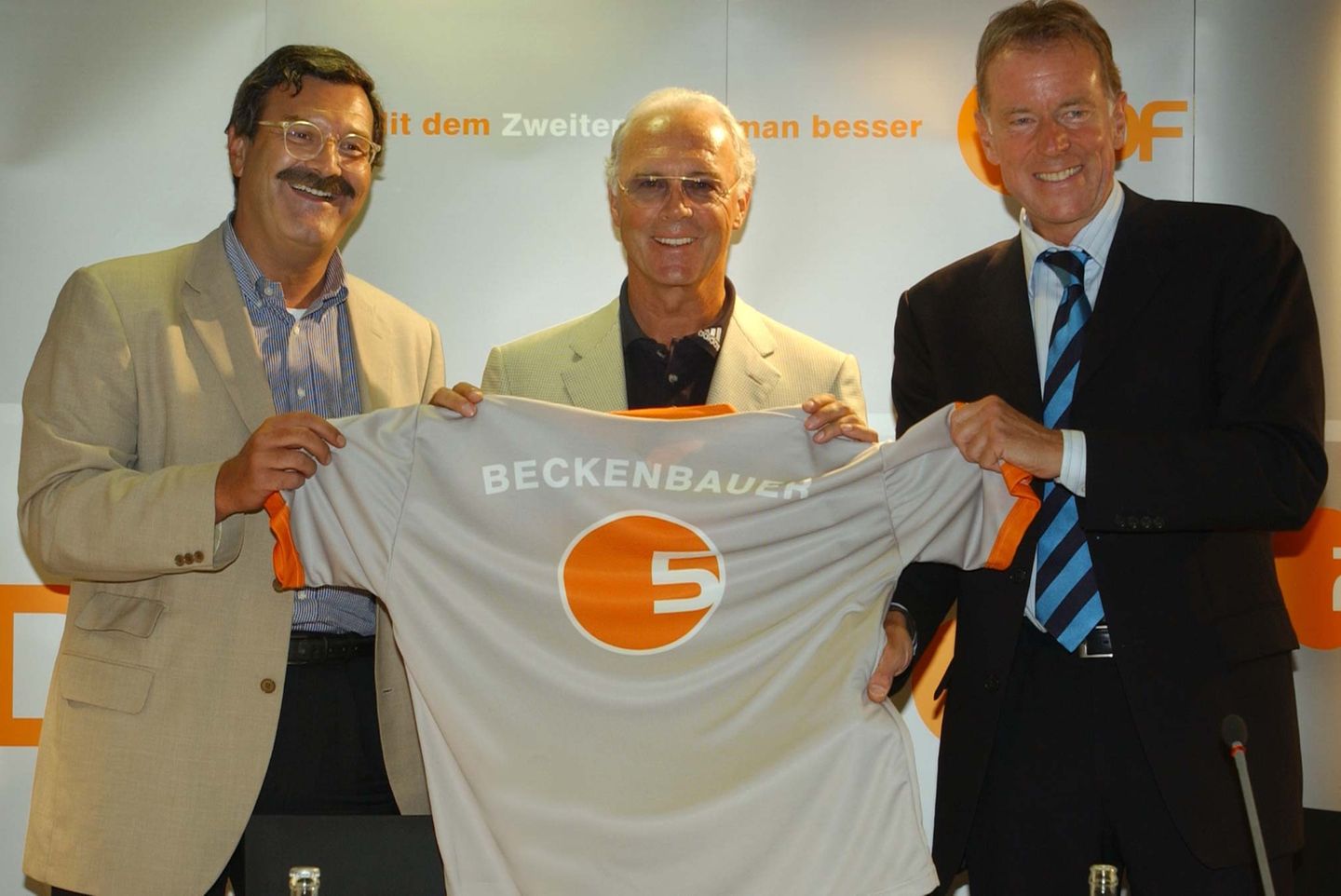 Zusammen mit ZDF-Chefredakteur Nikolaus Brender stellt "Poschi" 2003 den früheren Nationaltrainer Franz Beckenbauer als neuen ZDF-Fußballexperten vor - und überreicht dem Kaiser ein Trikot mit der Rückennummer 5.