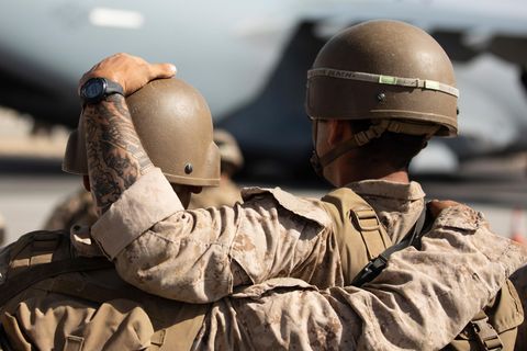 Von hinten sind zwei Soldaten in Tarnfleck und mit Helmen zu sehen. Einer legt dem anderen eine Hand auf den Helm