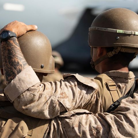 Von hinten sind zwei Soldaten in Tarnfleck und mit Helmen zu sehen. Einer legt dem anderen eine Hand auf den Helm