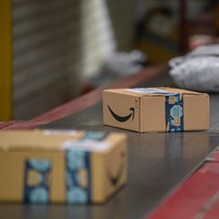 Amazon Pakete liegen im DHL-Paketzentrum auf einem Transportband.