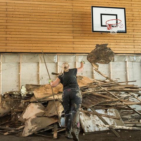Unter dem Basketballkorb werfen die Eltern die vom Hochwasser zerstoert Einrichtung auf einen Haufen