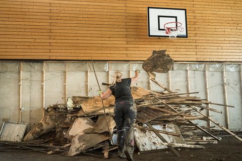Unter dem Basketballkorb werfen die Eltern die vom Hochwasser zerstoert Einrichtung auf einen Haufen