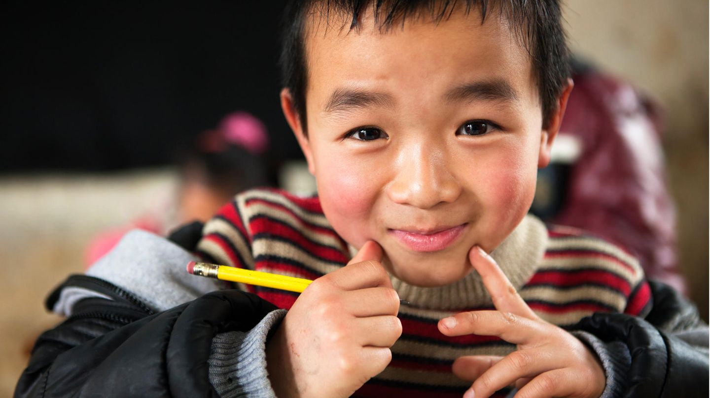 Junger chinesischer Schüler am Schultisch
