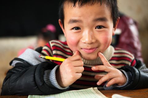 Junger chinesischer Schüler am Schultisch