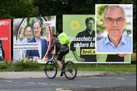Ein Radfahrer fährt an großen Wahlplakaten mit den Spitzenkandidaten der Bundestagswahl vorbei