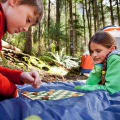Zwei Kinder spielen ein Brettspiel im Freien