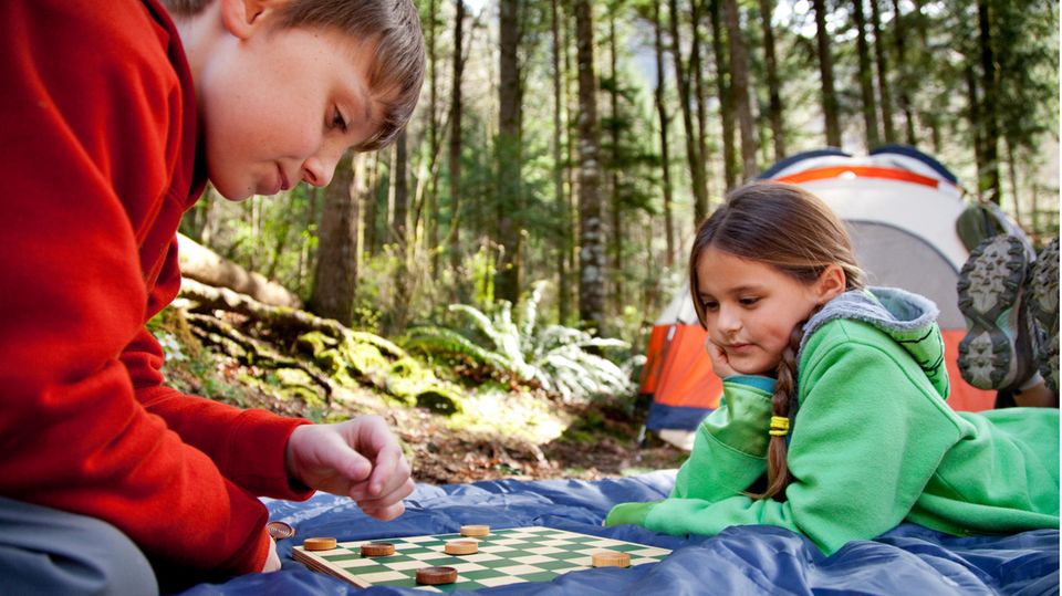 Zwei Kinder spielen ein Brettspiel im Freien