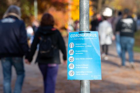 Ein Plakat mit Informationen über das Coronavirus ist an einem Weg im Westpark zu sehen