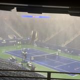 In einem leeren Tennis-Stadion mit lila Platz und grünem Außenbereich fällt Starkregen