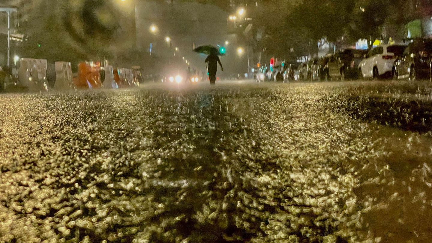 Im Dunkeln sind die Konturen eines Menschen zu sehen, der eine überflutete Straße hinunterläuft