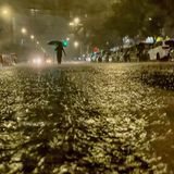 Im Dunkeln sind die Konturen eines Menschen zu sehen, der eine überflutete Straße hinunterläuft