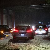 Im Dunkeln leuchten die Rücklichter mehrerer Autos, die auf einer überschwemmten Straße auf Staten Island fahren