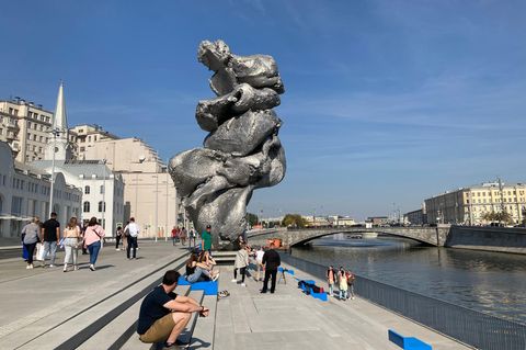 Menschen sitzen neben der Skulptur des Künstlers Urs Fischer in Moskau. Über das Aussehen des Kunstwerks wird gestritten.