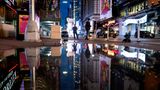 Die Neon-Reklamen des Times Square spiegeln sich in einer riesigen Pfütze