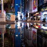 Die Neon-Reklamen des Times Square spiegeln sich in einer riesigen Pfütze