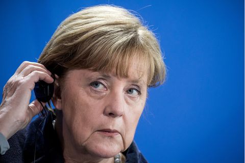 Bundeskanzlerin Angela Merkel hält einen Kopfhörer an ihr Ohr