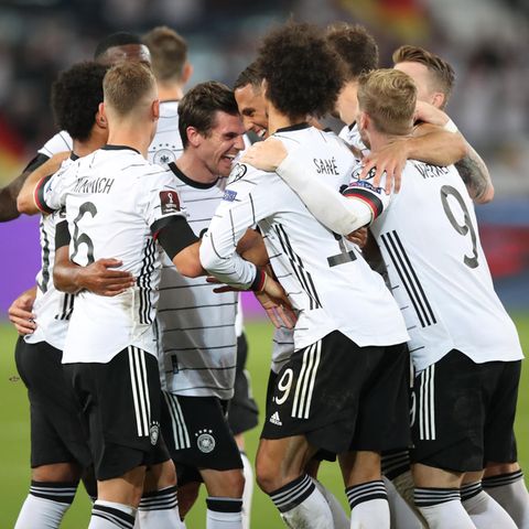 In weißen Trikots und schwarzen Hosen bilden alle zehn Feldspieler des DFB-Teams eine Jubeltraube um den Torschützen