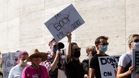 Eine Frau hält auf einer Demonstration ein Schild hoch, auf dem steht: "Mein Körper, meine Entscheidung".