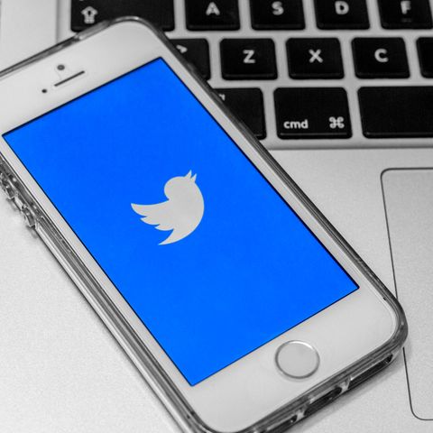Smartphone mit geöffneter Twitter-App liegt auf einem Laptop.