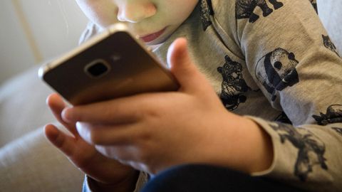 Ein kleines Mädchen schaut auf ein Smartphone