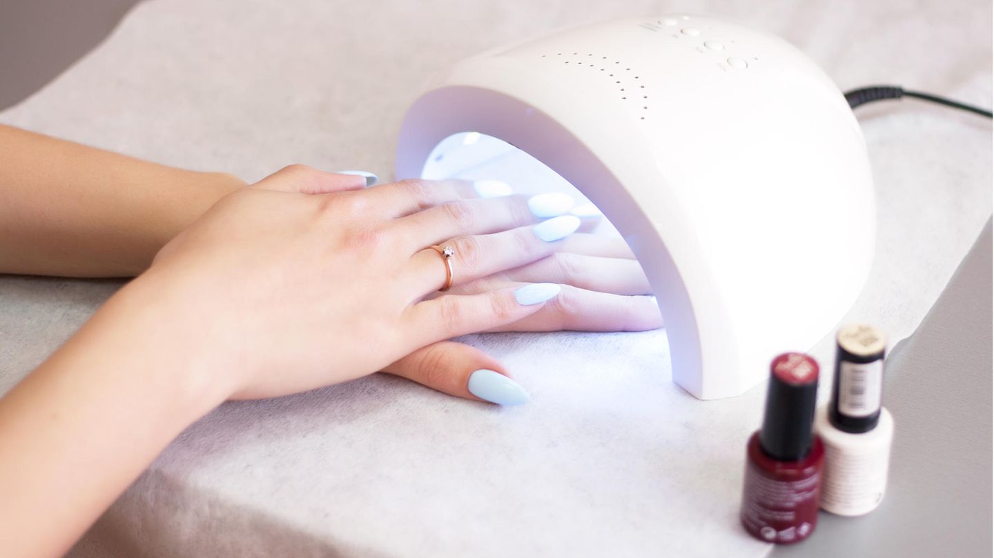 Frau härtet UV-Nagellack unter einem Nagelhärter