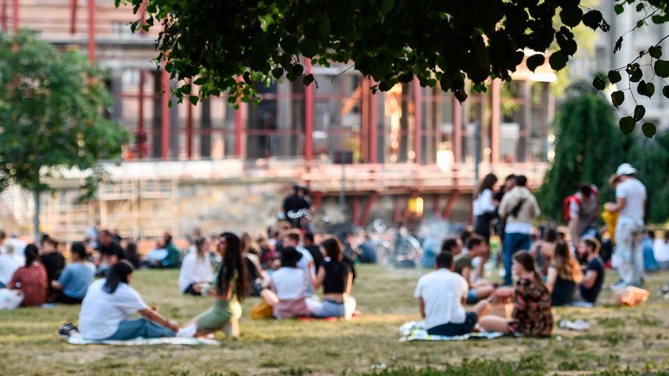 Neue Corona-Richtwerte Inzident Hospitalisierungsrate: Personen sitzen in einem Berliner Park