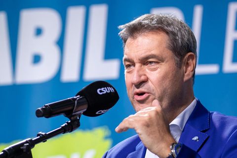 in blauem Jackett steht ein weißer Mann mit angegrauten schwarzen Haaren an einem Rednerpult und spricht in Mikro mit CSU-Logo