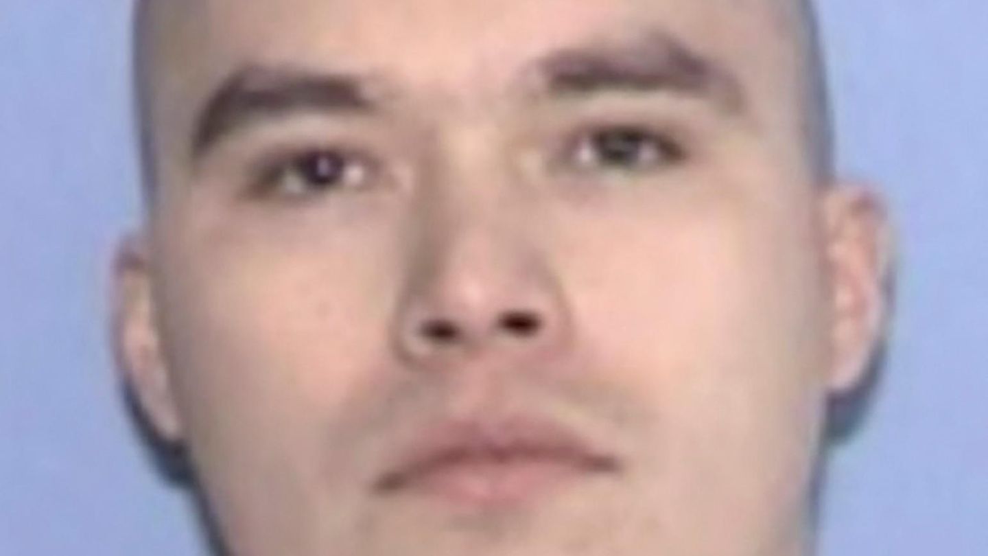 Ein weißer Mann mit kahl rasiertem Schädel und braunen Augen schaut direkt geradeaus