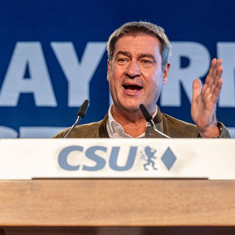 Hinter einem hölzernen Rednerpult mit "CSU"-Logo steht ein weißer Mann mit angegrauten Haaren und gestikuliert beim Sprechen