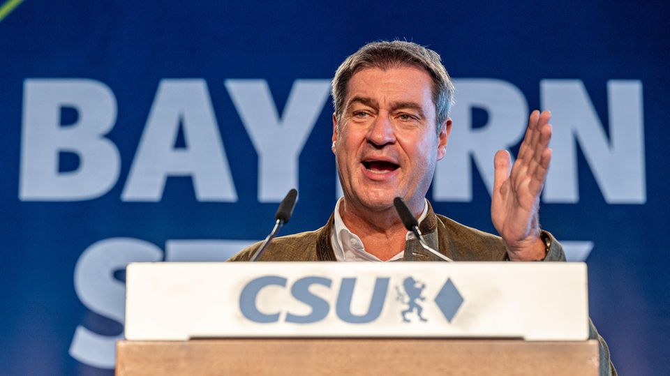 Hinter einem hölzernen Rednerpult mit "CSU"-Logo steht ein weißer Mann mit angegrauten Haaren und gestikuliert beim Sprechen