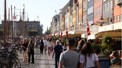 Passanten spazieren am Nyhavn in Kopenhagen entlang, dem bei Touristen beliebten Hafen mit seinen bunten Häuschen. 
