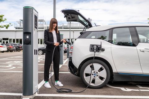 Autofahrerin lädt ihr Elektroauto an einer Ladesäule