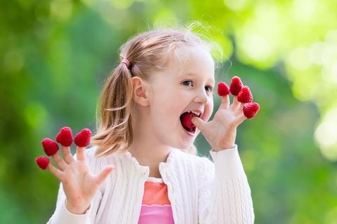 Kleines Mädchen isst Himbeeren