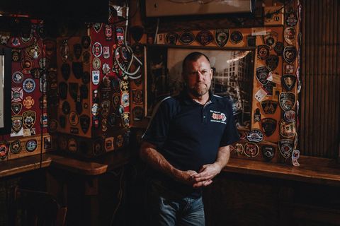 Tim Brown vor den Abzeichen von Feuerwehreinheiten aus dem ganzen Land