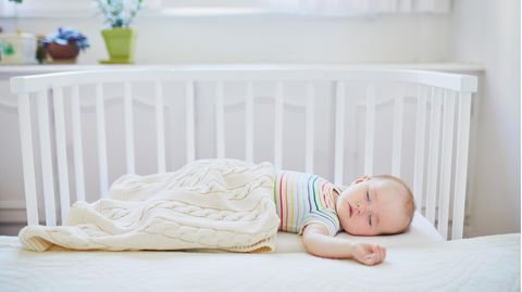 Beistellbetten für Babys: Kleiner Junge schläft zugedeckt in einem weißen Beistellbett